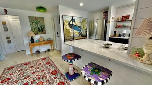 A modern kitchen with a marble countertop, a refrigerator, and a decorative wall piece. - Shovel Sand, Not Snow! You've found your Sanibel Island retreat! Secluded near-beach Strangler Fig home has it all.  Pet-friendly, too! (Sanibel)