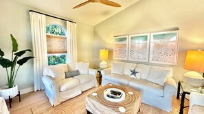 A living room with two white sofas, a coffee table, and a ceiling fan. - Surf Sound - Luxury 4BR Sanibel Home, Heated Pool, Cabana 5-Min Walk to Beach (Sanibel)