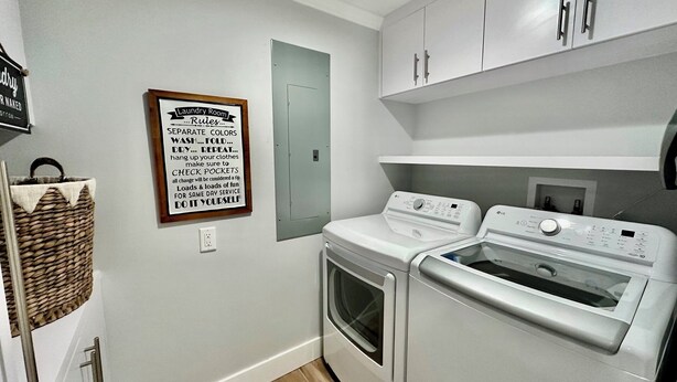 Une buanderie avec un panneau indiquant les règles à respecter pour le lavage du linge, un panier en osier et deux machines à laver LG blanches.
