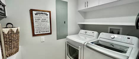 A laundry room with a sign detailing laundry rules, a wicker basket, and two white LG washing machines.