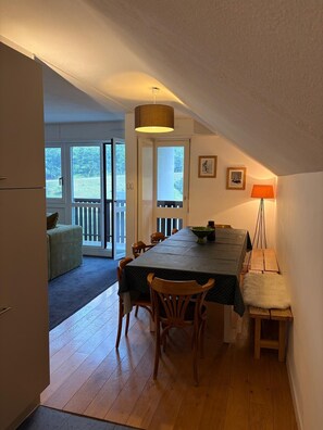 A dining area with a table, chairs, a lamp, and a view of the outdoors. - 300m from ski slopes, 4th floor, balcony, tv, 90m², Gourette (Eaux-Bonnes)