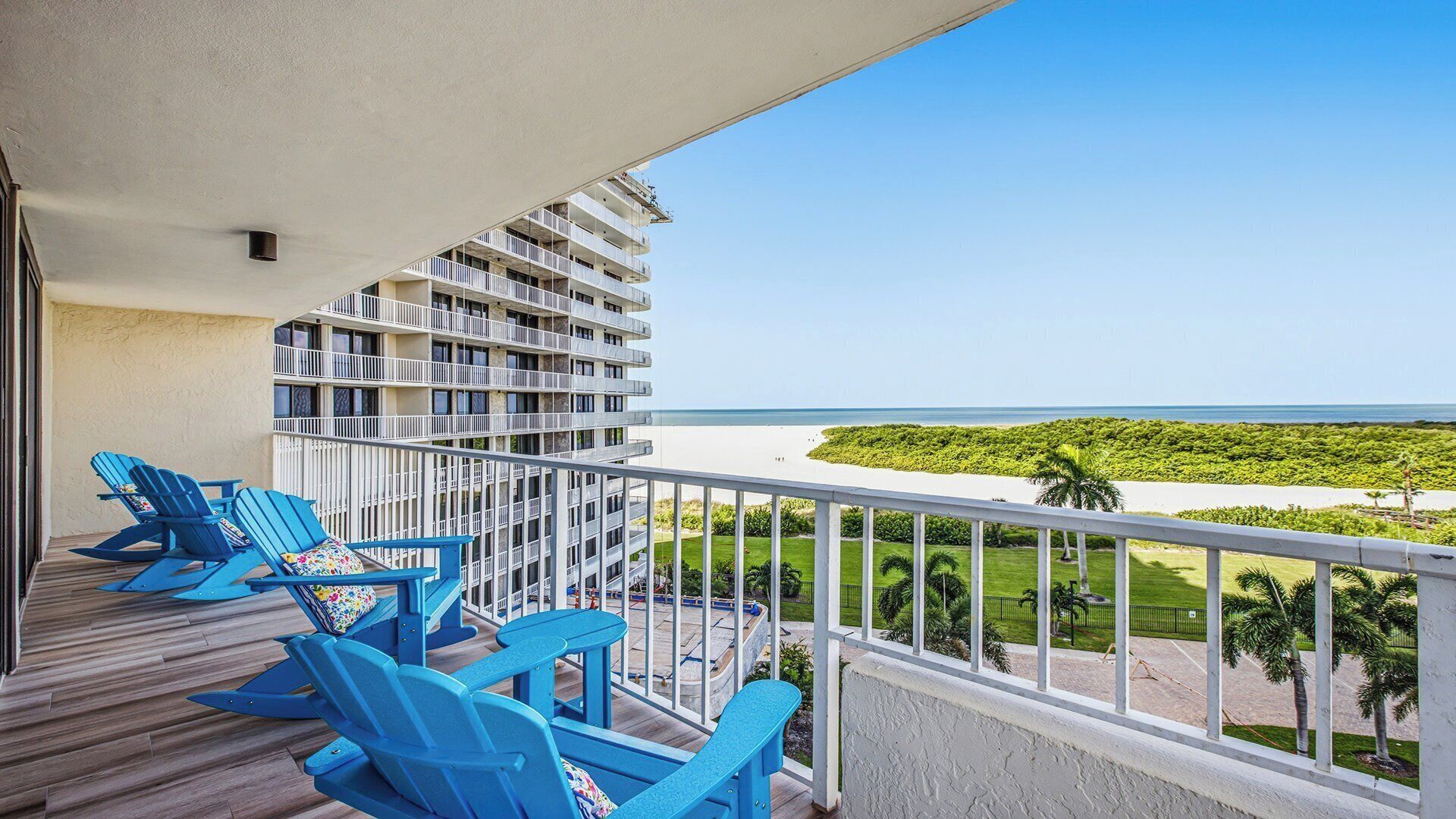 A balcony with blue chairs and a view of the ocean.