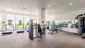 Una palestra moderna con tapis roulant, macchinari per pesi e pesi liberi.