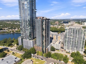 A high-rise building with multiple floors, surrounded by other buildings and a body of water. - Luxury Downtown Stay l Rooftop Pool & Skyline Views (Austin)