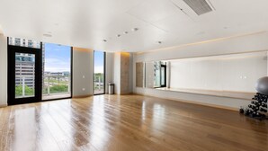 Une pièce spacieuse avec de grandes fenêtres, un plancher en bois et un mur recouvert de miroirs.