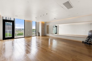 A spacious room with large windows, a wooden floor, and a mirrored wall. - Luxury Downtown Stay l Rooftop Pool & Skyline Views (Austin)