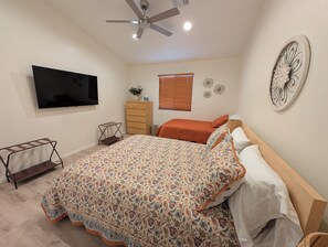 Ein Schlafzimmer mit einem Bett, einem Fernseher, einem Deckenventilator, einer Kommode und einer Wanddekoration.