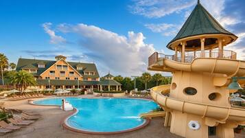 A resort with a large pool, a water slide, and a building with multiple balconies.