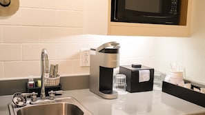 Una cocina con una cafetera Keurig, un fregadero y un microondas.