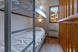 Ein kleines Zimmer mit Stockbetten, einem Fenster mit Blick auf ein Gebäude und einer Holzhackenwand.