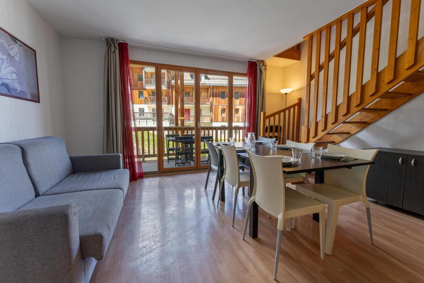 Ein modernes Wohnzimmer mit einer Couch, einem Esstisch, Stühlen und einer Treppe.