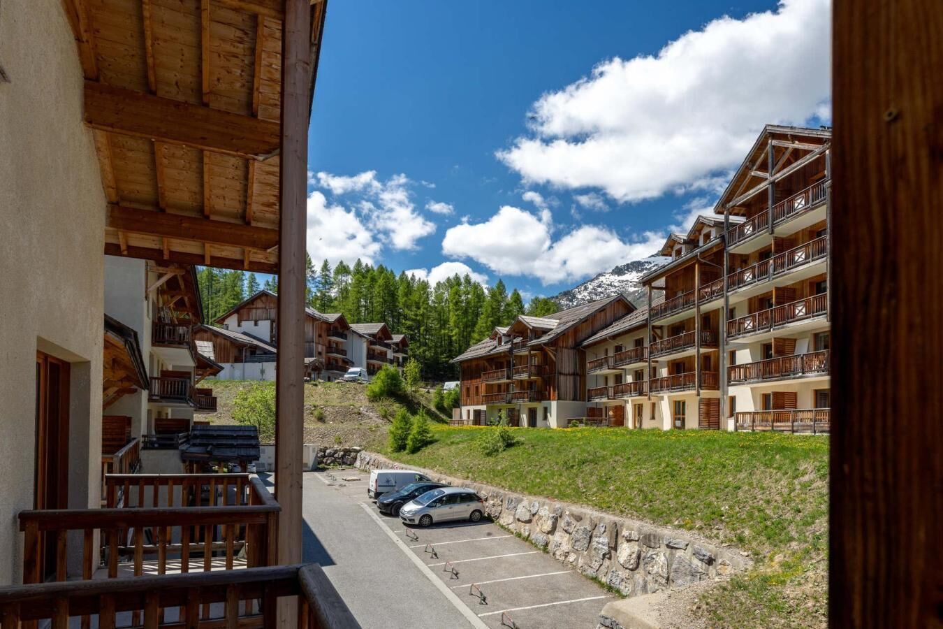 Un chalet de montagne doté de plusieurs balcons, d’un espace de stationnement et offrant une vue sur la forêt et les montagnes environnantes.