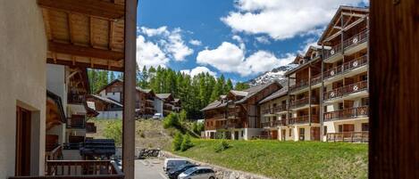 A mountain lodge with multiple balconies, a parking area, and a view of the surrounding forest and mountains.