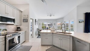 A modern kitchen with white cabinetry, a built-in oven, and a large window. - Waterleaf Ct, 363 in Marco Island, FL (Marco Island)