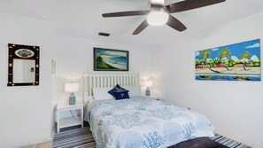 A bedroom with a bed, two bedside tables, a ceiling fan, a painting, and a mirror. - Waterleaf Ct, 363 in Marco Island, FL (Marco Island)