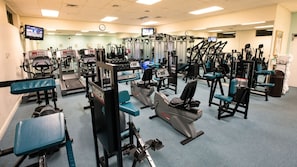A gym with various exercise equipment, including treadmills, weight machines, and a stationary bike.