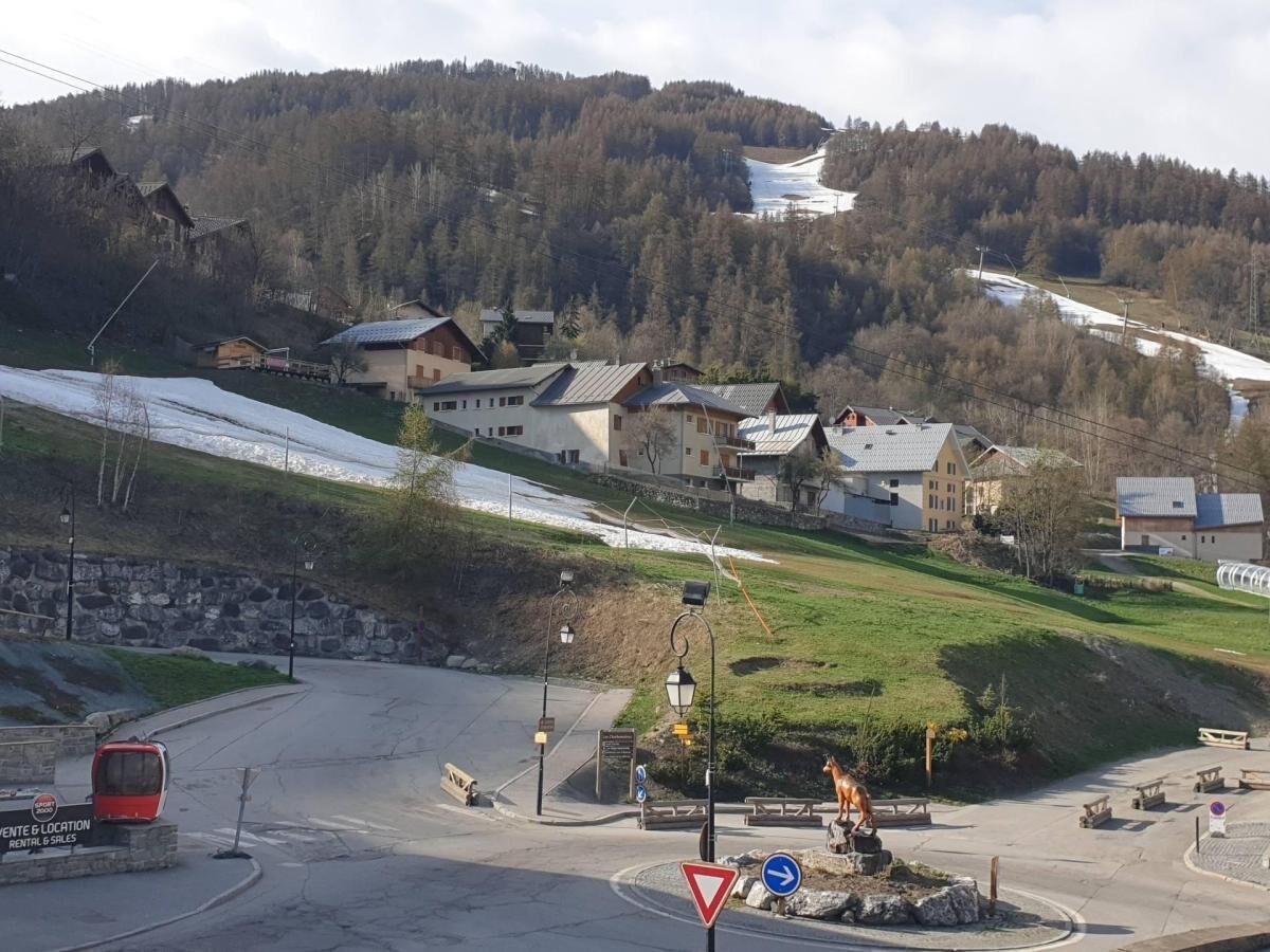 Ein Bergdorf mit Häusern, einer Seilbahn und einer Straße, die bergauf führt.