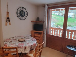 A dining area with a table set for two, a clock, and a television on a stand. - 120m from ski slopes, 2nd floor, balcony, parking, tv, ski locker, 28m², Valloire (Valloire)