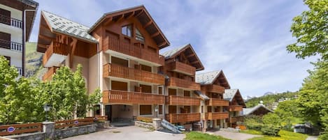 A multi-story hotel with wooden balconies and a paved entrance area.