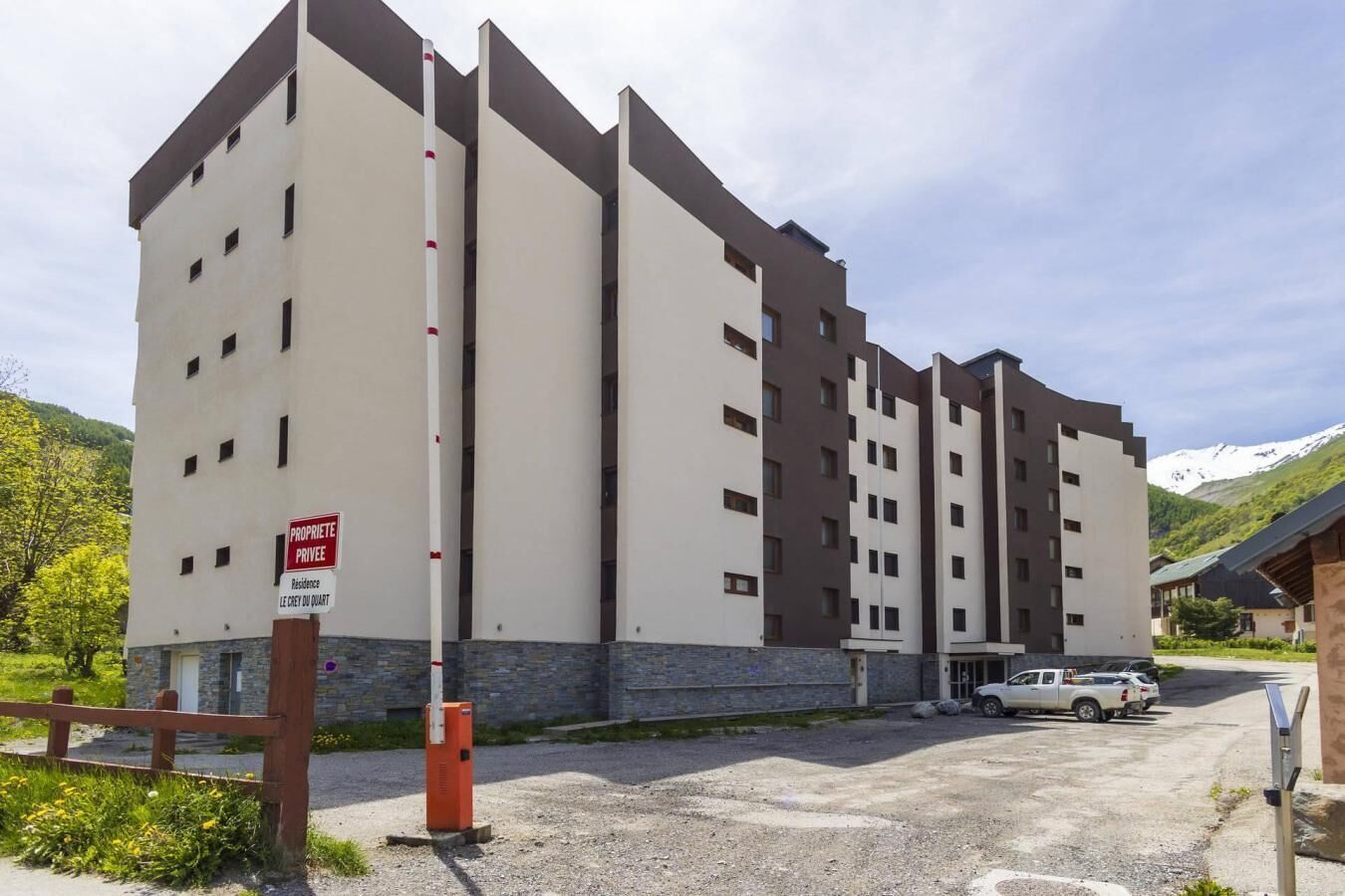 Een meerhoog hotel met een modern architectonisch ontwerp, met een combinatie van beige- en donkerbruine kleuren, en een bordje met de tekst 'Particuliere eigendom'.