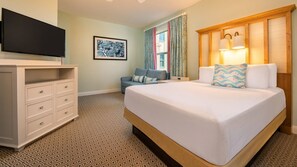 A hotel room with a bed, a dresser, a television, a framed picture, and a window with curtains. - Vero Beach | Relaxed Beach Retreat | Pool + Beach | 2BR Villa (Vero Beach)