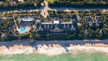 Vue aérienne d’un complexe hôtelier comprenant un grand bâtiment, une piscine et une plage.