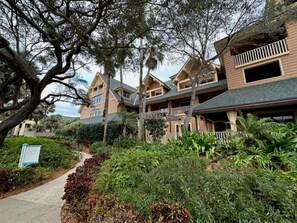 A multi-story hotel with a landscaped garden, a pathway, and a signboard.