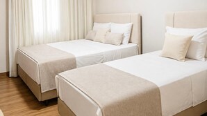 Une chambre d’hôtel avec deux lits, une fenêtre avec des rideaux et un plancher en bois.