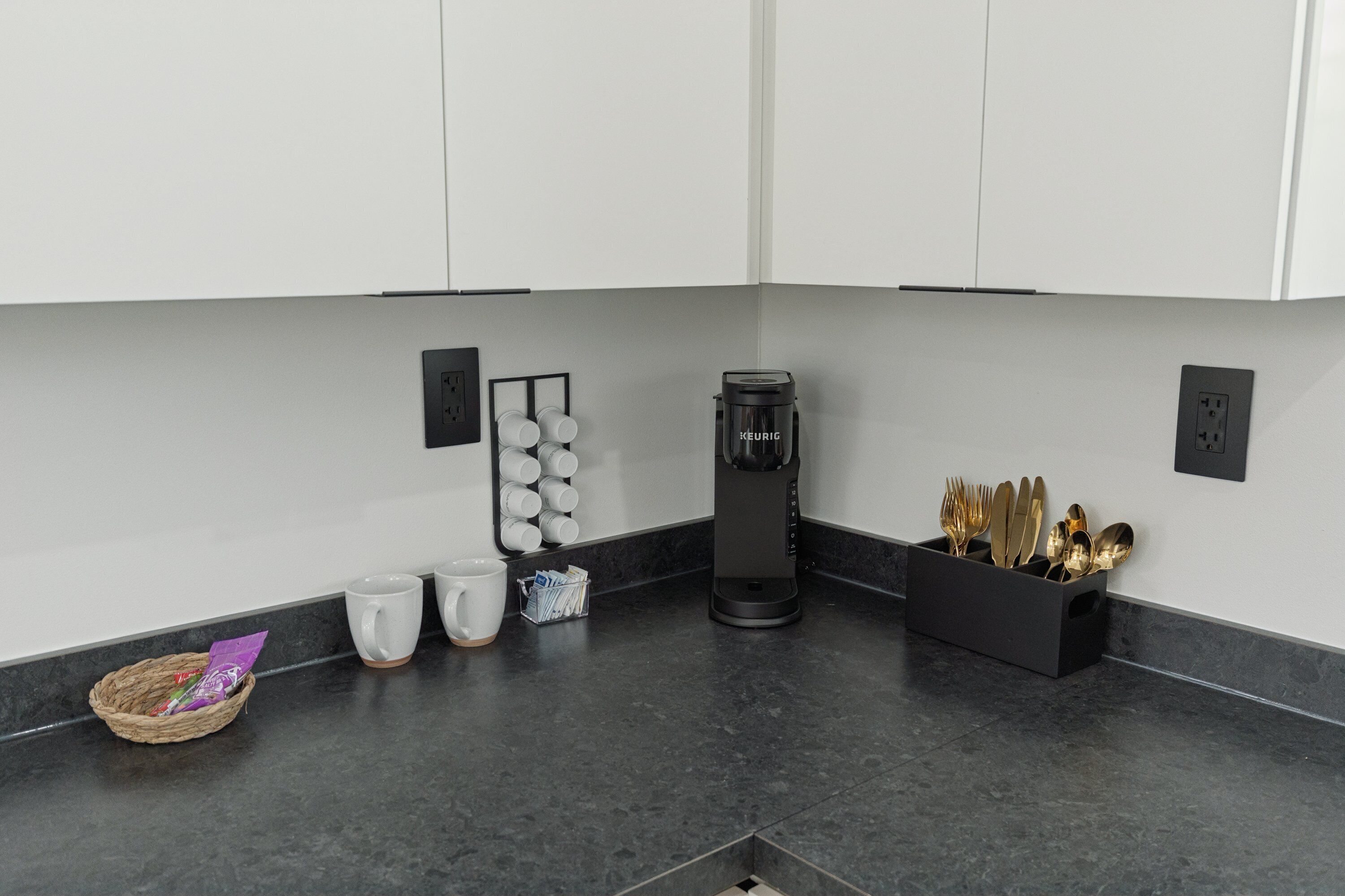 Una cocina moderna con armarios blancos, una cafetera y un portalapices.