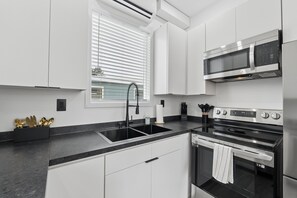 Une cuisine moderne équipée d’une cuisinière en acier inoxydable, d’un four à micro-ondes encastré et d’un évier à deux bacs.
