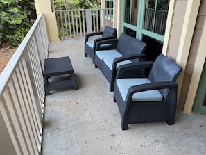 A covered outdoor seating area with wicker furniture and a concrete floor. - Vero Beach | Private Coastal Retreat | Pool + Beach | 3BR Sleeps 12 Cottage (Vero Beach)