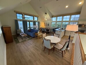 A spacious living area with a dining table, sofas, and a kitchen area with a large island. - Vero Beach | Private Coastal Retreat | Pool + Beach | 3BR Sleeps 12 Cottage (Vero Beach)