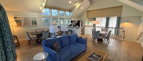 A spacious living area with a blue sofa, coffee table, and dining table.
