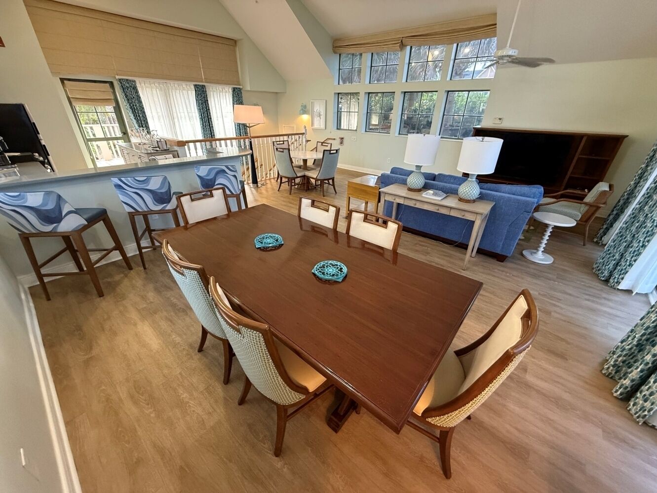 Un grand espace à manger comprenant une table et des chaises en bois, un canapé et un téléviseur.