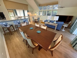 A spacious dining area with a wooden table and chairs, a sofa, and a television. - Vero Beach | Private Coastal Retreat | Pool + Beach | 3BR Sleeps 12 Cottage (Vero Beach)