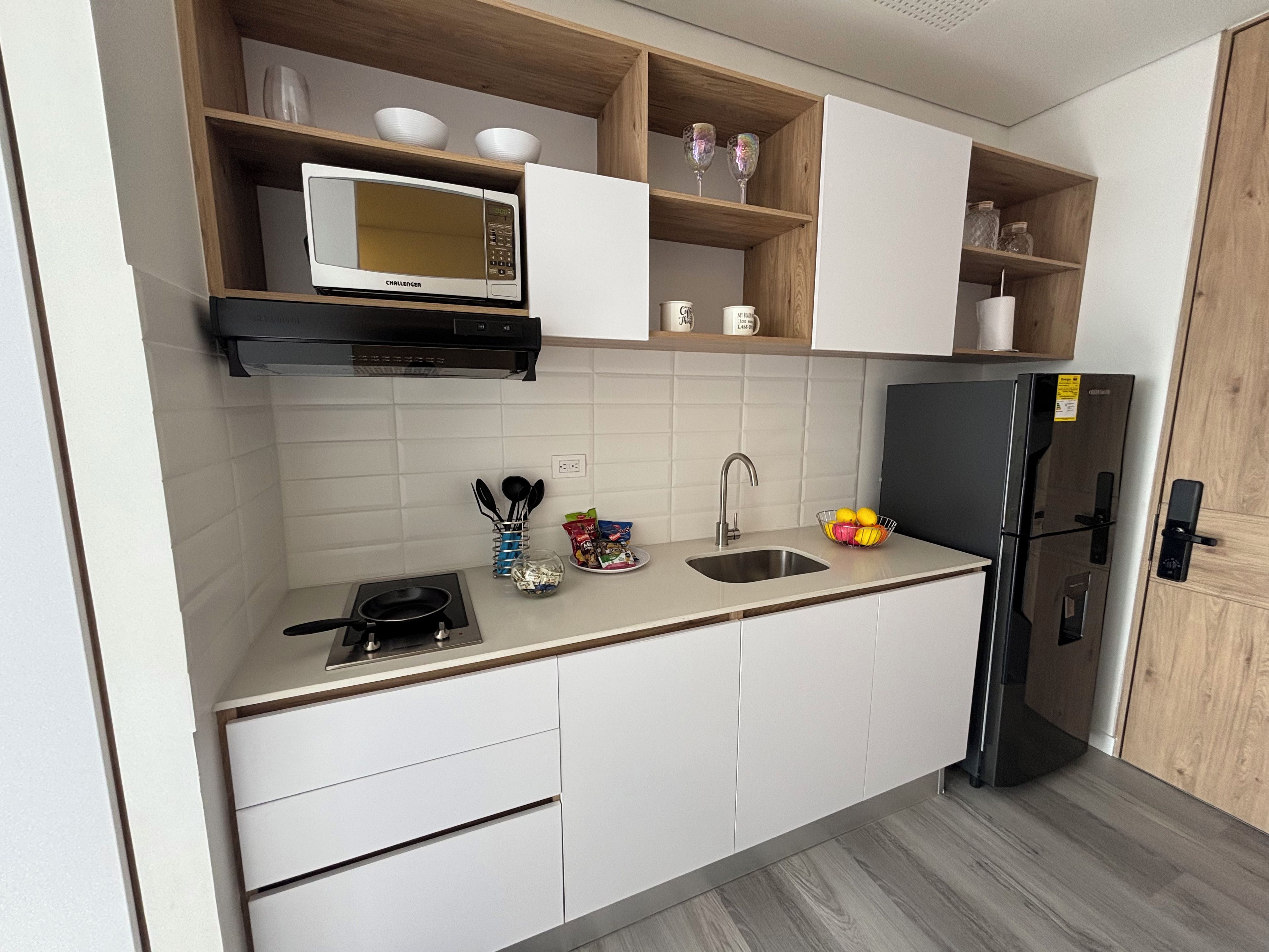 A compact kitchen with a microwave, sink, and a black refrigerator.
