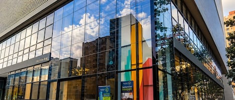 Un edificio moderno con amplios ventanales que reflejan el cielo y las nubes.