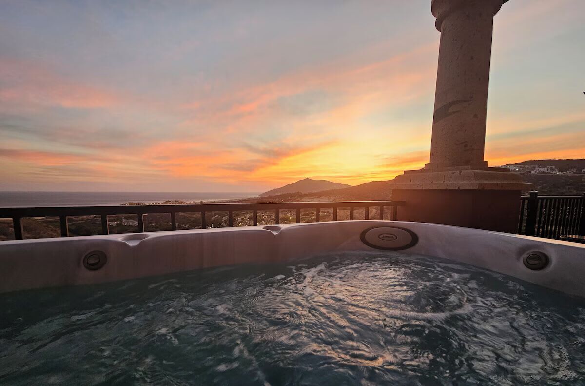 A hot tub with a view of a sunset and a mountain in the background.