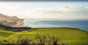 A coastal golf course with a flagstick, ocean views, and a sandy beach. - Ocean Private Villa at Montecristo Pueblo Bonito (Cabo San Lucas)