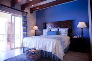 A bedroom with a bed, two bedside lamps, a nightstand, a basket, and a view of a balcony. - Ocean Private Villa at Montecristo Pueblo Bonito (Cabo San Lucas)