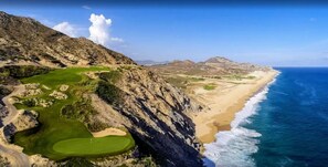 Een kustlandschap met een golfbaan, strand en rotskliffen.