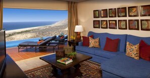 A living room with a sofa, a coffee table, and a view of the beach. - Ocean Private Villa at Montecristo Pueblo Bonito (Cabo San Lucas)
