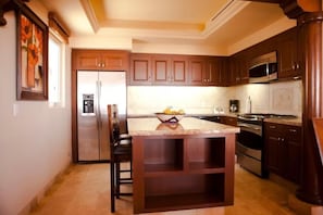 A kitchen with wooden cabinets, a stainless steel refrigerator, a microwave, and a stove. - Ocean Private Villa at Montecristo Pueblo Bonito (Cabo San Lucas)