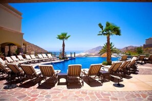 A poolside area with lounge chairs and a view of the ocean. - Ocean Private Villa at Montecristo Pueblo Bonito (Cabo San Lucas)