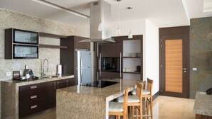 Una cucina moderna con piani di lavoro in granito, elettrodomestici in acciaio inossidabile e un'isola centrale con sgabelli da bar.
