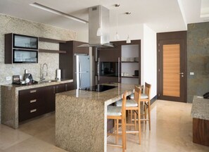 Eine moderne Küche mit Granit-Arbeitsplatten, Edelstahlgeräten und einer zentralen Kochinsel mit Barhocker.