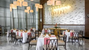 Ein Restaurant mit mehreren Tischen, Stühlen und hängenden Pendelleuchten.