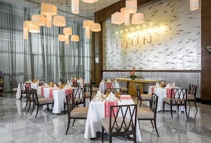Ein Restaurant mit mehreren Tischen, Stühlen und hängenden Pendelleuchten.