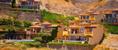 Un quartier résidentiel situé sur une colline, avec des maisons à plusieurs étages, une piscine et un paysage rocheux.