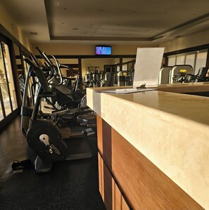A gym with exercise equipment, a television on the wall, and a counter with a whiteboard. - Beautiful Oceanview Villa at Pueblo Bonito (Cabo San Lucas)